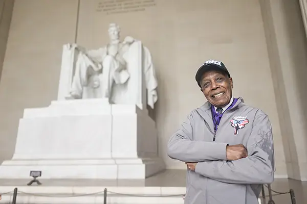 A man stands in front of the Lincoln Memorial.