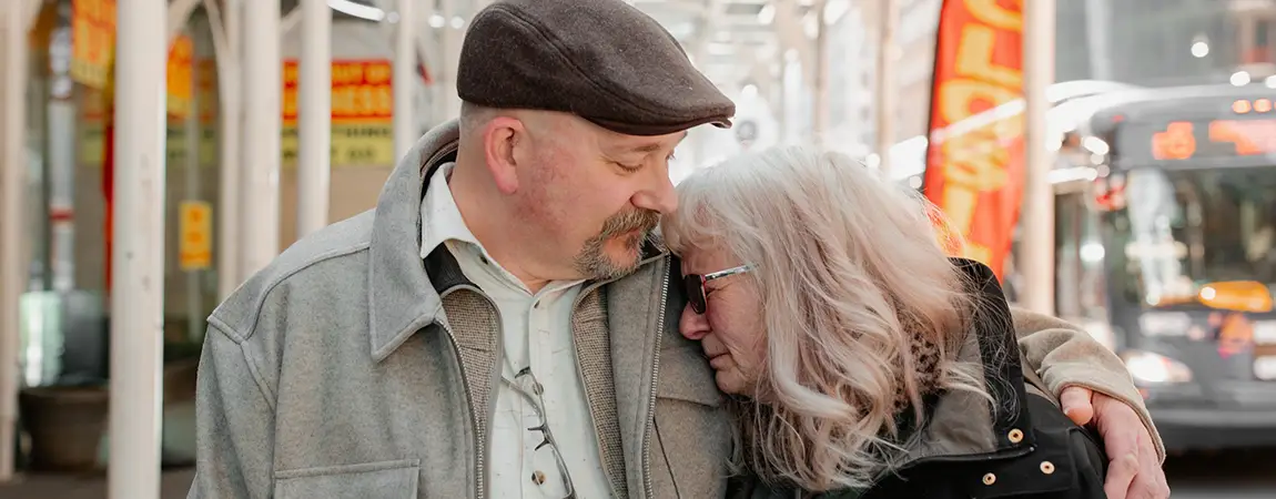 An older woman cries on the shoulder of a man.