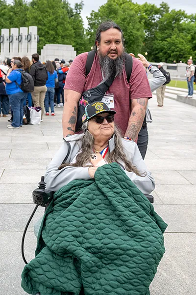 A man pushes an older woman in a wheelchair