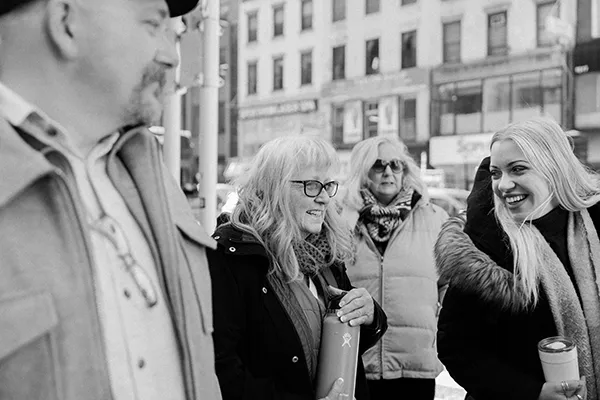 People in jackets stand outside on a city street.