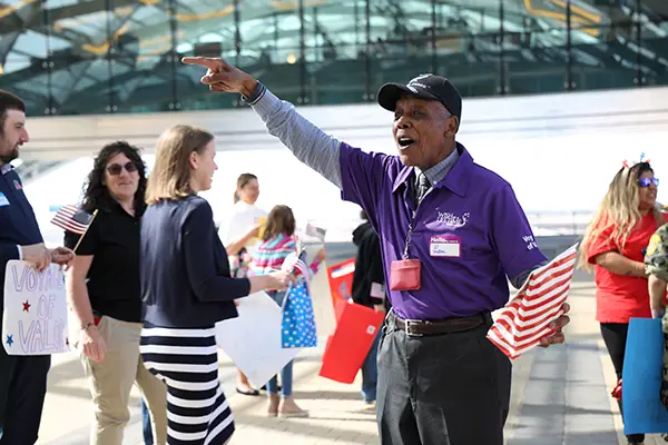 AARP-wish-national-siblings-day A man talks and points in a crowd of people.