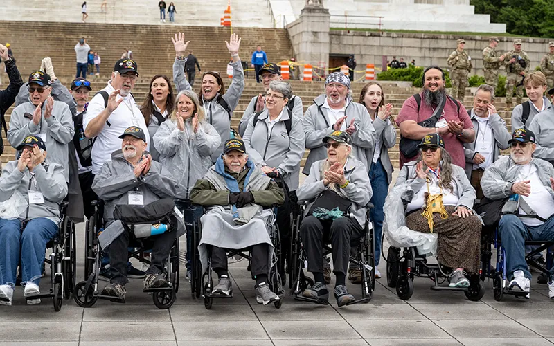 A group of people in wheelchairs cheer with others people who are standing