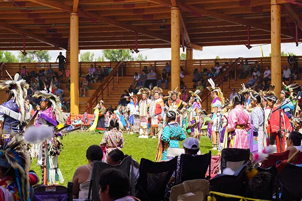 Native Americans in traditional clothing stand in an outdoor stadium.