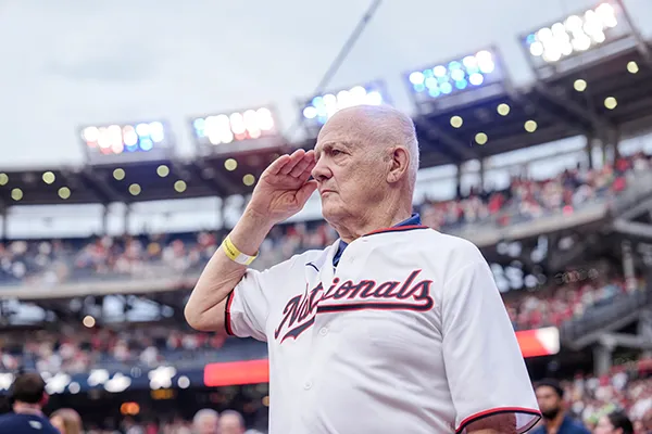 A man salutes during a baseball game.