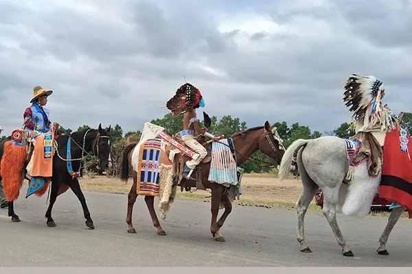 Native Americans ride horses in a parade.