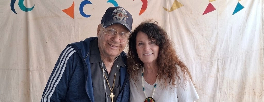 A Native American man and woman stand together in a tipi. 
