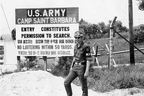 A young man in an Army uniform stands outside the U.S. Army’s Camp Saint Barbara.