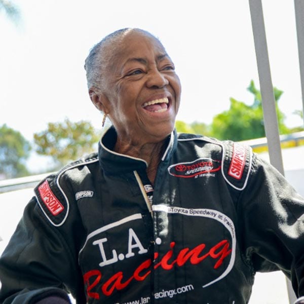 Wish of a Lifetime wish recipient laughing at the camera while wearing car racing gear